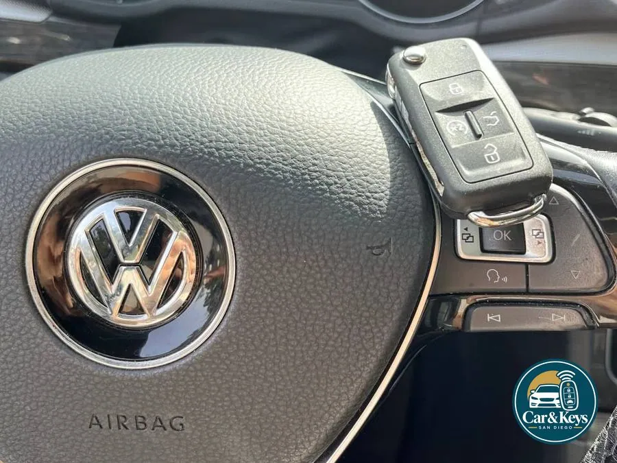 A Volkswagen key in hand at the wheel